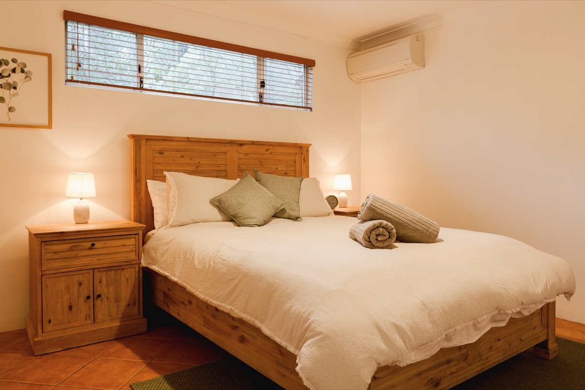 Queen bedroom with timber bed, quality linen and bedside lamps at River Reach Chalet