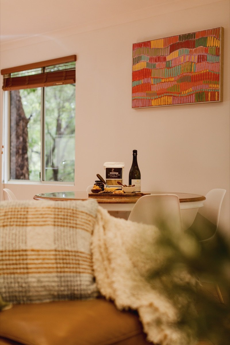A welcome of local wine and treats on the dining table at River Reach Chalet, Margaret River