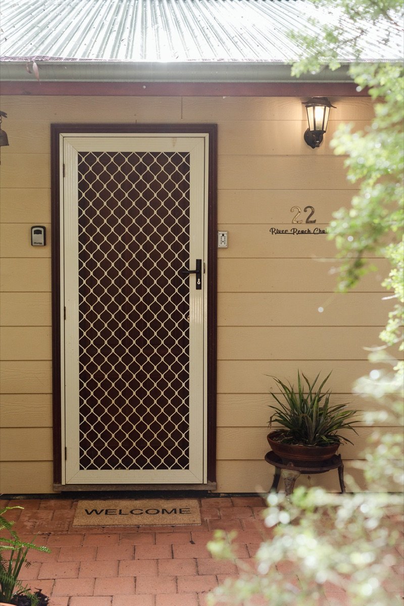 Front door of the chalet with welcome mat and potted plants