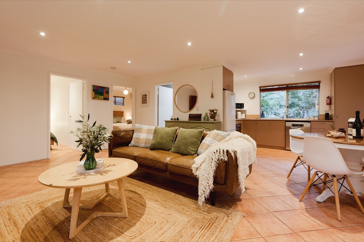 Open-plan living and dining at River Reach Chalet with leather sofa, jute rug and forest outlook