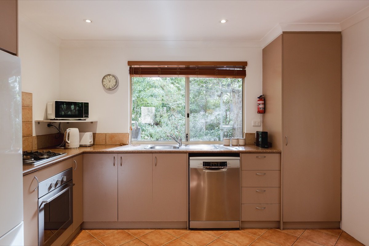 Fully equipped kitchen at the chalet with oven, cooktop, microwave and a window onto the forest